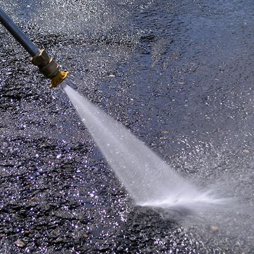 Power washer spraying a high-pressure stream across pavement